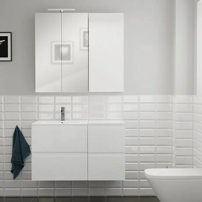 Camargue Espacio Badmöbel-Set i83 - 100 cm, Gama weiß glänzend - Badezimmer-Szene mit einem weißen Waschtischunterschrank und Spiegelschrank. Ein dunkles Handtuch hängt seitlich am Schrank.