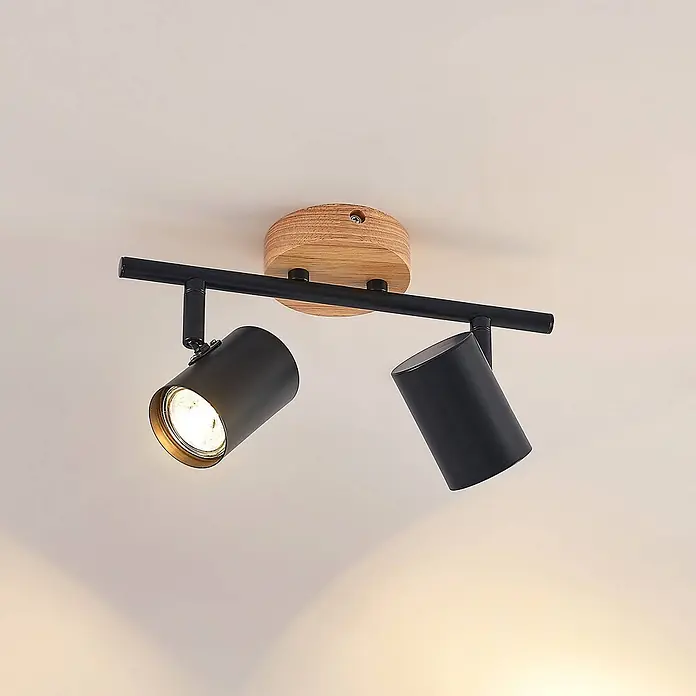 Lindby Deckenleuchte Xiomara - Holz hell, schwarz, GU10 - Schwarzer Metall-Deckenstrahler mit zwei verstellbaren Köpfen und Holzsockel, ein Licht leuchtet.