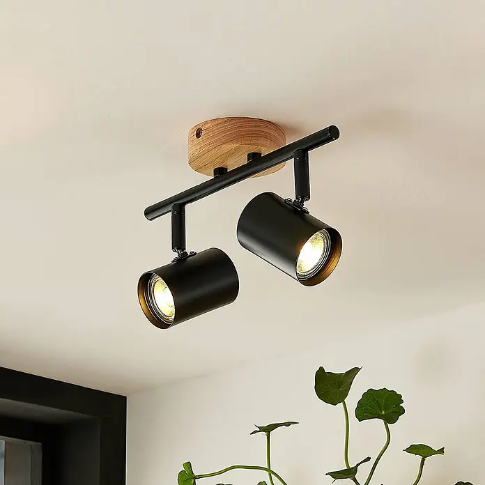 Lindby Deckenleuchte Xiomara - Holz hell, schwarz, GU10 - Zwei schwarze Deckenstrahler aus Metall und Holz, die warmes Licht abgeben.