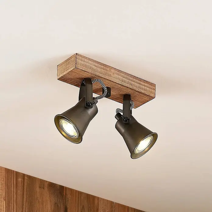 Lindby Deckenstrahler Grandesa - Holz dunkel, schwarz, GU10 - Zwei dunkle Metallstrahler mit geflochtenen Kabeln auf rustikaler Holzdeckenleuchte, beleuchtet.