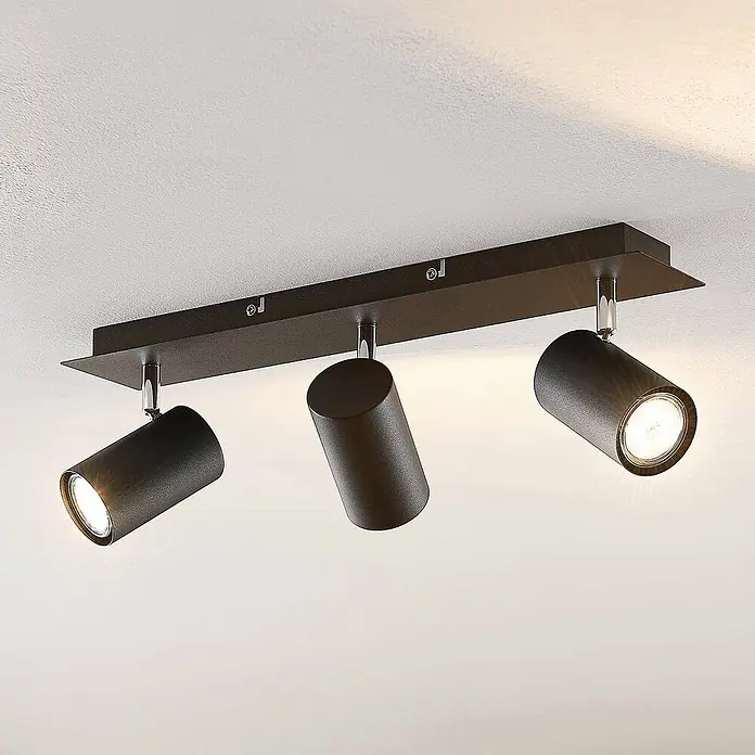 Lindby Deckenstrahler Joffrey - L x B x H: 49 x 9,5 x 16,5 cm, schwarz, schwarz, GU10 - Dunkelbraune Dreifach-Deckenleuchte mit verstellbaren zylindrischen Strahlern, auf rechteckigem Sockel montiert und beleuchtet.