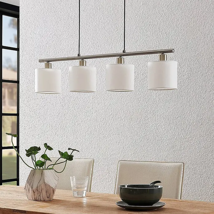 Lindby Pendelleuchte Stannis - L x B x H: 75 x 12 x 13,5 cm, weiß / opal, nickel matt, weiß, E14 - Vierflammige Pendelleuchte mit gebürsteter Metallstange und weißen zylindrischen Schirmen, über einem Esstisch hängend.
