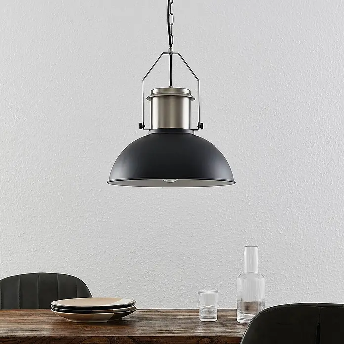 Lindby Pendelleuchte Freitjof - schwarz, Schwarz matt, nickel matt, E27 - Pendelleuchte im Industriestil mit schwarzem Schirm und satin-nickel Oberteil über einem Esstisch aus Holz.