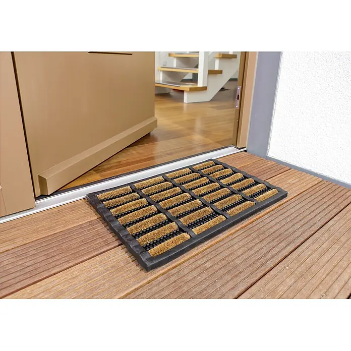 Astra Fußmatte Rimini - Materialmix, Schwarz/Natur, 40 x 60 cm - Fußmatte aus Kokosfaser vor einer geöffneten Haustür auf einer Holzterrasse, ideal zum Sauberhalten des Eingangsbereichs.