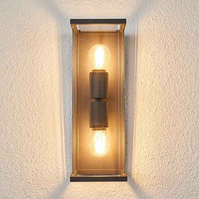 Lucande Außenwandleuchte Annalea - schwarz, klar / transparent, IP54 - Rechteckige Wandleuchte mit dunklem Rahmen und bronzefarbenem Interieur, mit zwei leuchtenden Filamentbirnen, an einer strukturierten Wand montiert.
