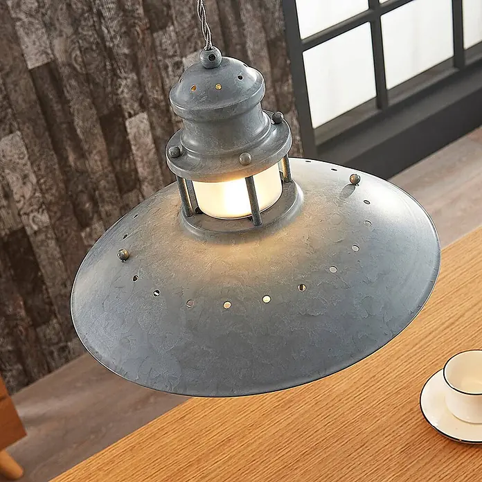 Lindby Pendelleuchte Louisanne - L x B x H: 35 x 35 x 25,7 cm, alu / grau / zink, grau-Grün, klar, E27 - Graue Pendelleuchte im Industriestil aus Metall, beleuchtet, über einem Holztisch hängend.
