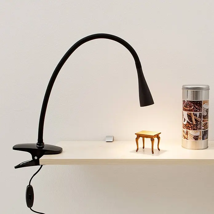 Lindby Klemmleuchte Baris - Farbe Gehäuse: schwarz - Schwarze flexible LED-Klemmleuchte an heller Ablage, beleuchtet Miniaturtisch und Kaffeedose.