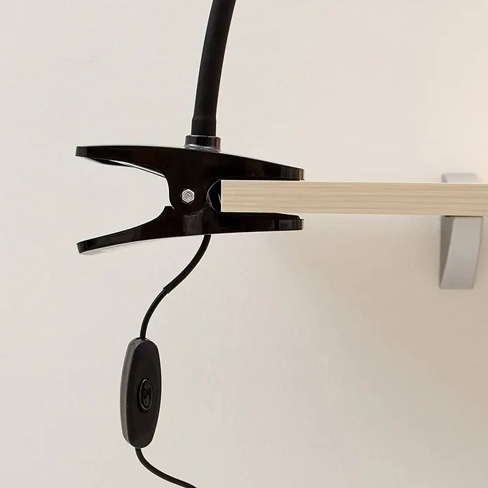 Lindby Klemmleuchte Baris - Farbe Gehäuse: schwarz - Schwarze Klemmleuchte mit flexiblem Hals und Schnurschalter, an einem hellen Holzregal geklemmt.