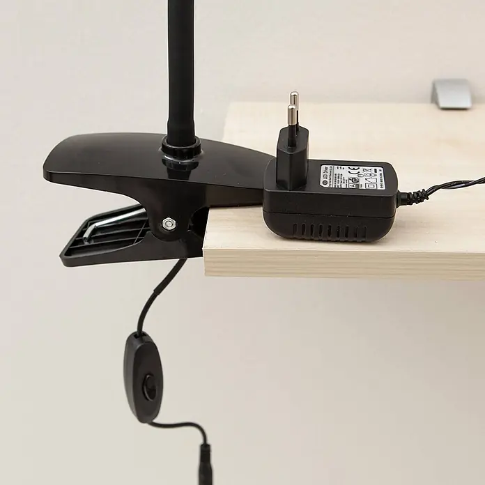 Lindby Klemmleuchte Baris - Farbe Gehäuse: schwarz - Schwarze Klemmlampe an einem hellen Holzregal befestigt, mit einem schwarzen LED-Treiber-Netzteil und einem Kabelschalter.