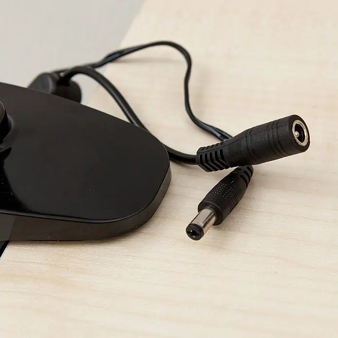 Lindby Klemmleuchte Baris - Farbe Gehäuse: schwarz - Schwarzes DC-Stromverlängerungskabel mit Stecker- und Buchsenanschluss, verbunden mit einem schwarzen Elektronikgerät.