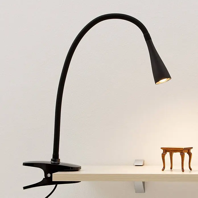 Lindby Klemmleuchte Baris - Farbe Gehäuse: schwarz - Schwarze, flexible LED-Klemmleuchte mit Schwanenhals, die ein helles Holzregal beleuchtet.