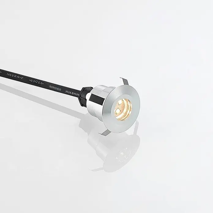 Lindby LED-Gartenstrahler Gracelle - 3.000 K - Kleine, runde, silberne Einbau-LED-Leuchte mit warmem Licht, verbunden mit einem schwarzen Kabel.
