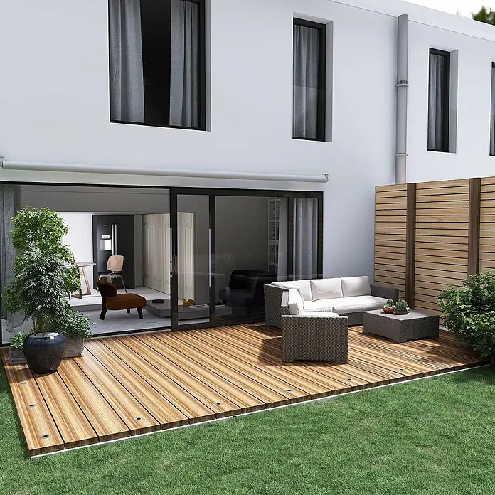 Lindby LED-Gartenstrahler Gracelle - 3.000 K - Ein großes Holzdeck erstreckt sich von einem modernen Haus, möbliert mit Sitzgelegenheiten im Freien, umgeben von grünem Gras.