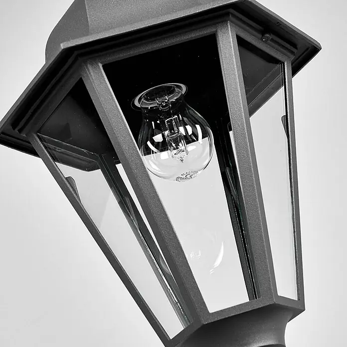 Lindby Außenwand- & Deckenleuchte Edana - schwarz, schwarz, IP44 - Nahaufnahme einer dunkelgrauen traditionellen Außenlaterne mit klaren Glasscheiben und sichtbarer Glühbirne.