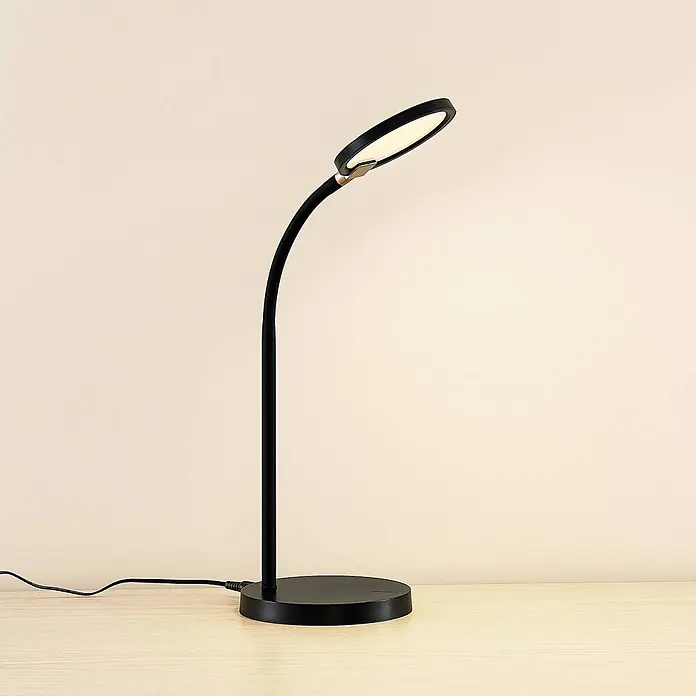 Lindby Tischleuchte Binera - schwarz, schwarz - Schwarze flexible LED-Schreibtischlampe mit rundem Kopf und Fuß auf einem Holzschreibtisch.