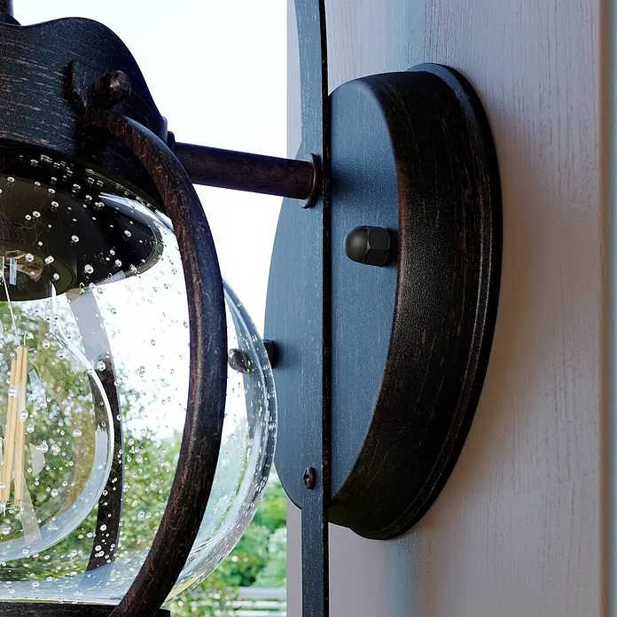 Lindby Außenwandleuchte Gerlo - braun / rost, IP23 - Dunkelbronzene Außenwandleuchte mit blasigem Glas, an einer Wand montiert.