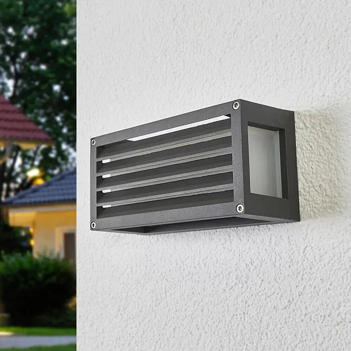 Lucande Außenwandleuchte Aurelien - schwarz, IP54 - Anthrazitfarbene, rechteckige Außenwandleuchte mit Lamellendesign, an einer strukturierten Außenwand montiert.