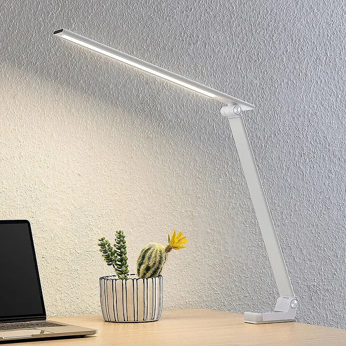 Prios Tischleuchte Tamarin - L x B x H: 40,6 x 9,5 x 40 cm, weiß / opal, weiß / opal - Weiße, schmale LED-Schreibtischlampe mit Gelenkdesign, beleuchtet einen Holztisch neben Laptop und Pflanzen.