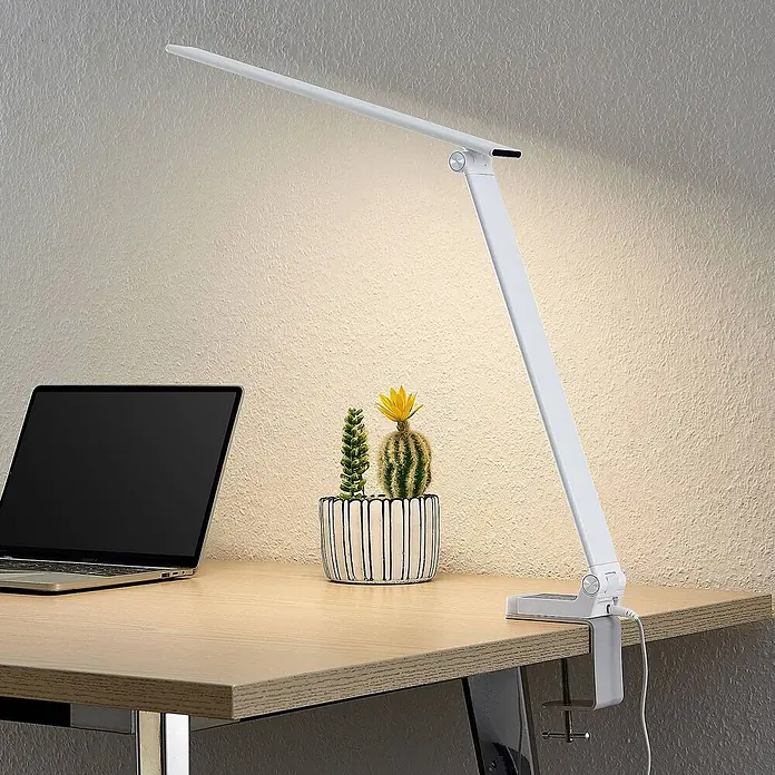 Prios Tischleuchte Tamarin - L x B x H: 40,6 x 9,5 x 40 cm, weiß / opal, weiß / opal - Weiße, moderne LED-Schreibtischlampe mit verstellbarem Arm und Klemmfuß, die einen Holztisch mit Laptop beleuchtet.