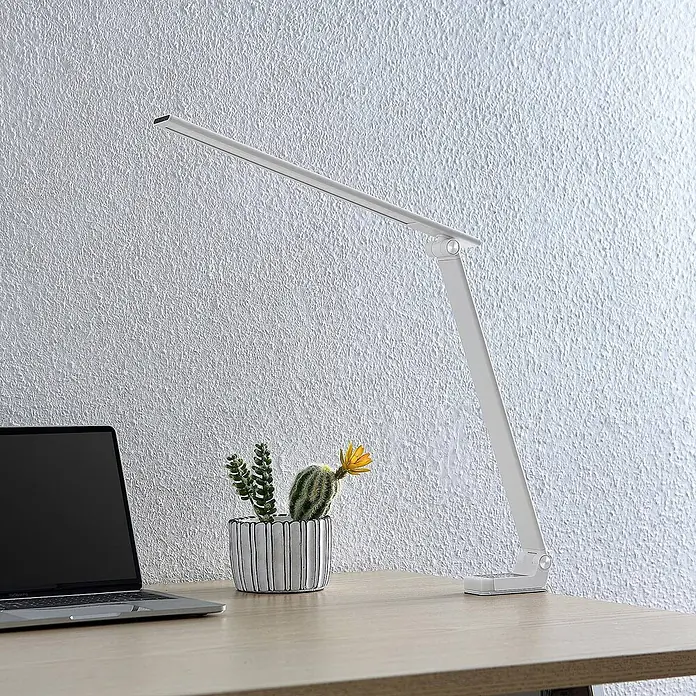 Prios Tischleuchte Tamarin - L x B x H: 40,6 x 9,5 x 40 cm, weiß / opal, weiß / opal - Schlanke, silberne, verstellbare Schreibtischlampe auf einem Holztisch mit Laptop und Kaktus.