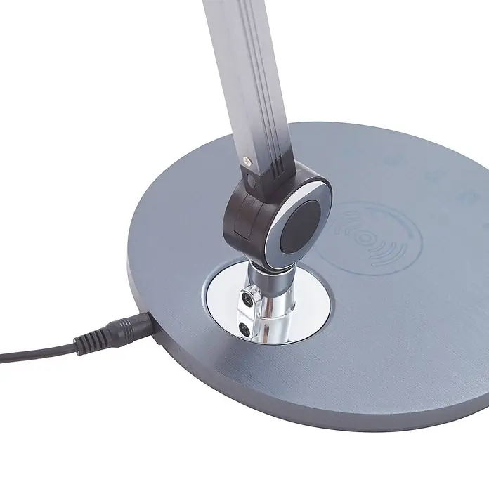 Lindby Tischleuchte Nyxaris - alu / grau / zink, alu / grau / zink - Nahaufnahme eines grauen, runden Schreibtischlampenfußes mit flexiblem Arm, integrierter Ladefläche und angeschlossenem Stromkabel.