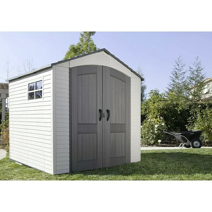 Lifetime Gerätehaus Fox - Außenbreite inkl. Dachüberstand: 215 cm, Außentiefe inkl. Dachüberstand: 210 cm, Kunststoff, Lichtgrau/Anthrazit - Ein großes Kunststoff-Gartenhaus mit Doppeltüren und einem kleinen Fenster unter blauem Himmel mit einem Rasen davor.
