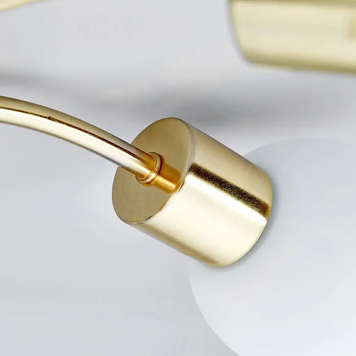 Lindby Deckenleuchte Elaina - messing / gold, E14 - Goldfarbener Messing-Lampenarm, verbunden mit zylindrischer Basis, neben einem weißen kugelförmigen Lampenschirm.