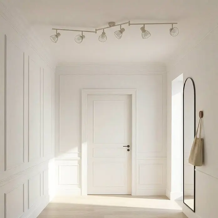 Lindby Deckenleuchte Piena - L x B x H: 150 x 9,3 x 22 cm, creme / amber, creme / amber, E14 - Eine Schienenbeleuchtung mit mehreren verstellbaren Strahlern und Käfigschirmen, an der Decke eines Flurs montiert.