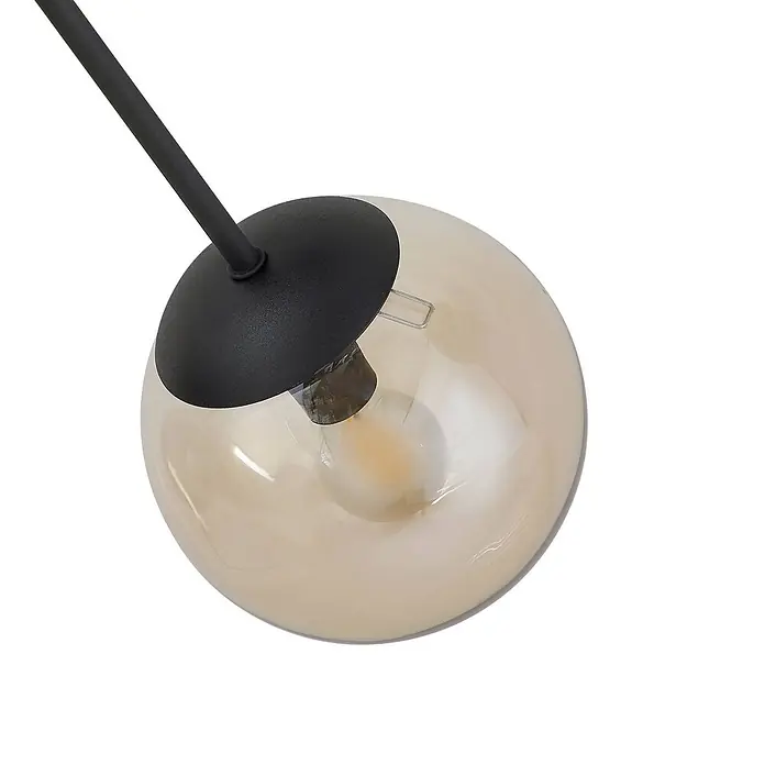 Lindby Deckenleuchte Isamer - schwarz, alu / grau / zink, E14 - Nahaufnahme einer Lampe mit schwarzem Metallarm, schwarzem Sockel und einer kugelförmigen bernsteinfarbenen Glasschirm mit Glühbirne.