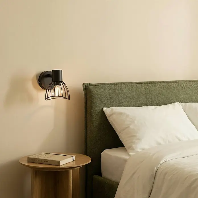 Lindby Deckenleuchte Piena - schwarz, schwarz, E14 - Schwarze Wandleuchte aus Metallgeflecht mit sichtbarer Glühbirne, neben einem Bett montiert.