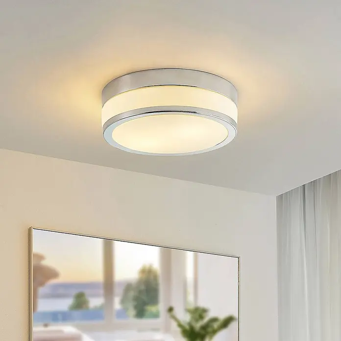 Lindby Deckenleuchte Flavi - L x B x H: 28 x 28 x 9 cm, chrom / silber, E27 - Eine moderne, runde Chrom-Deckenleuchte mit weißem Diffusor beleuchtet einen Raum.
