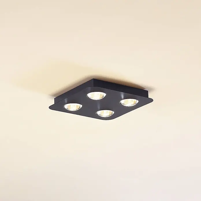 Lindby Deckenleuchte Jyla - L x B x H: 25 x 25 x 4,2 cm, schwarz, 2GX53 - Schwarzer quadratischer Deckenstrahler mit vier warm leuchtenden Lampen an einer hellen Decke.