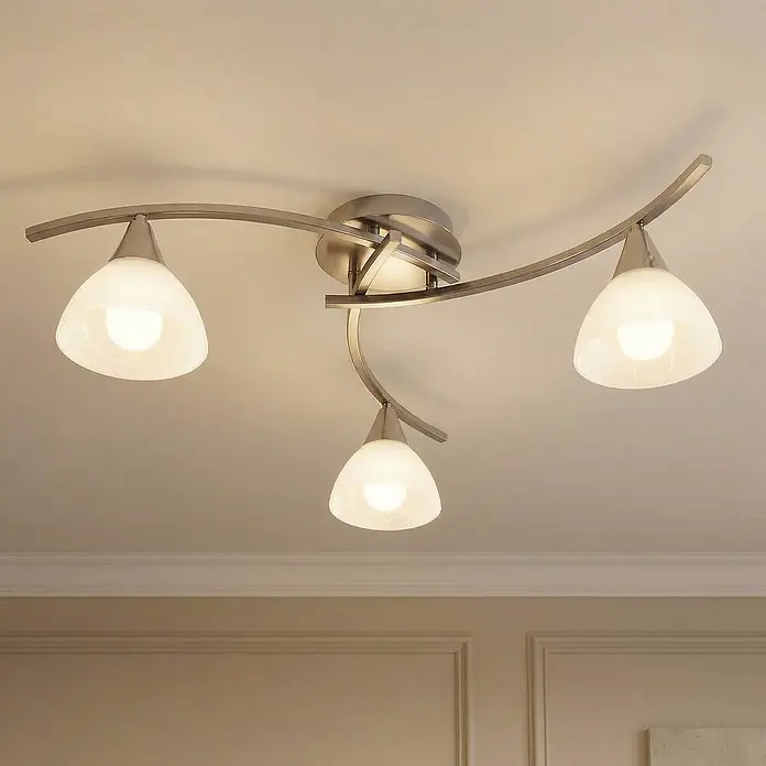 Lindby Deckenleuchte Della - alu / grau / zink, E14 - Moderne Deckenleuchte mit drei geschwungenen Armen aus gebürstetem Metall und weißen Glasschirmen, die einen Raum beleuchtet.