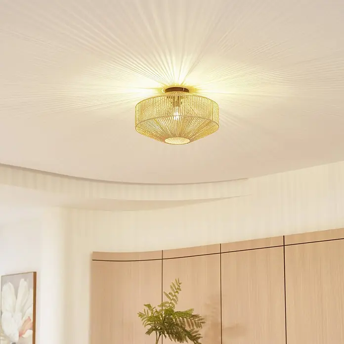 Lindby Deckenleuchte Sorino - Holz hell, E27 - Goldfarbene Deckenleuchte mit gewebtem Schirm, die einen Raum beleuchtet und radiale Lichtmuster an die Decke wirft.