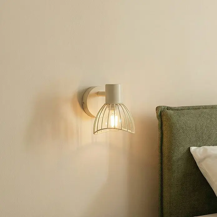 Lindby Deckenleuchte Piena - creme / amber, creme / amber, E14 - Wandleuchte mit hellfarbenem Metallkäfigschirm, an einer Wand neben einem grünen Kopfteil montiert.
