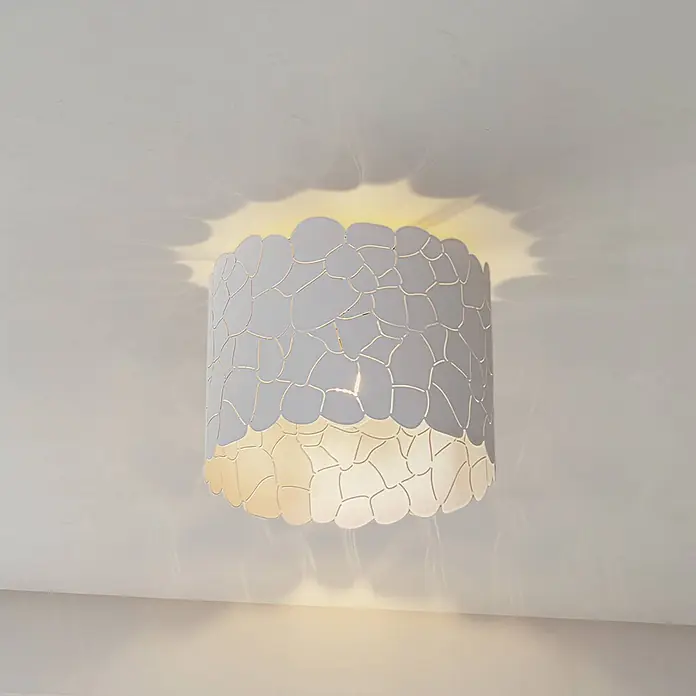 Lindby Deckenleuchte Aralena - weiß / opal, E27 - Graue zylindrische Deckenleuchte mit unregelmäßig gemusterten Aussparungen, die dekorative Licht- und Schatteneffekte an Decke und Wände wirft.