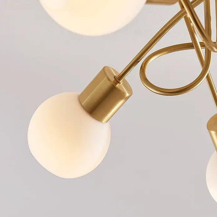 Lindby Deckenleuchte Elaina - messing / gold, E14 - Nahaufnahme einer modernen Messingleuchte mit leuchtenden kugelförmigen Glasdiffusoren.