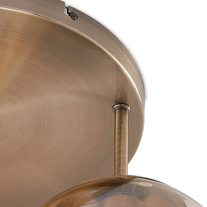 Lindby Deckenleuchte Teeja - bronze / altmessing, creme / amber, E27 - Nahaufnahme einer Deckenleuchte aus gebürsteter Bronze: runder Sockel, Stützstange und Oberseite eines Glasschirms.