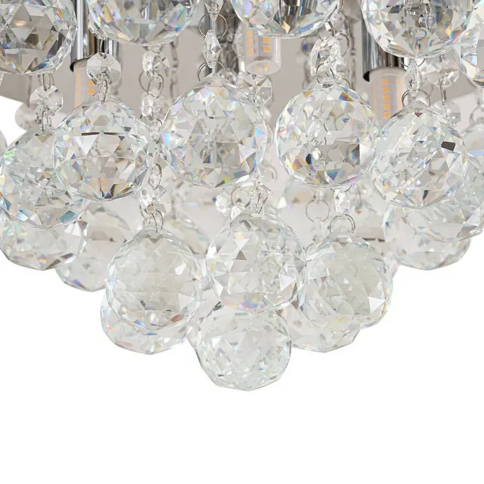 Lindby Deckenleuchte Antonino - chrom / silber, klar / transparent, G9 - Nahaufnahme einer modernen Leuchte mit mehreren facettierten klaren Kristallkugeln und sichtbaren LED-Lampen.