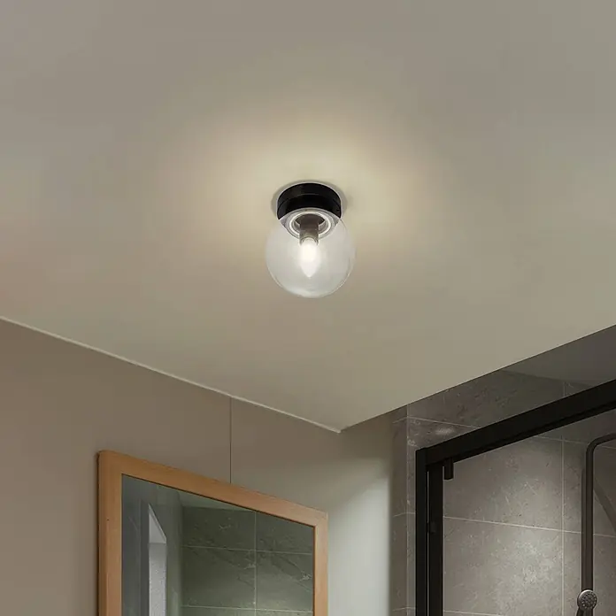 Lucande Deckenleuchte Badolo - schwarz, klar / transparent, E14 - Schwarze Deckenleuchte mit klarer Glaskugel beleuchtet einen Raum.