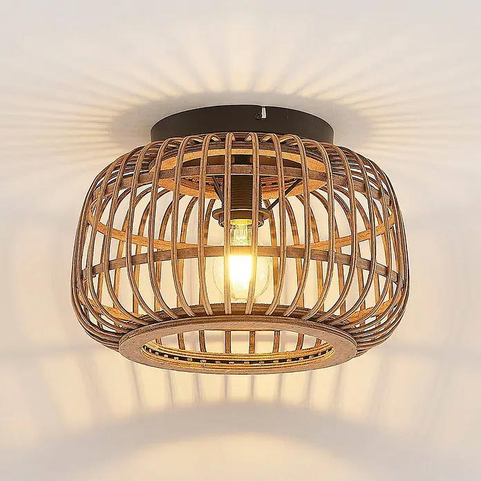 Lindby Deckenleuchte Bominio - Holz hell, E27 - Deckenleuchte aus Rattan mit dunklem Metallsockel und sichtbarer Glühbirne, wirft dekorative Lichtmuster.