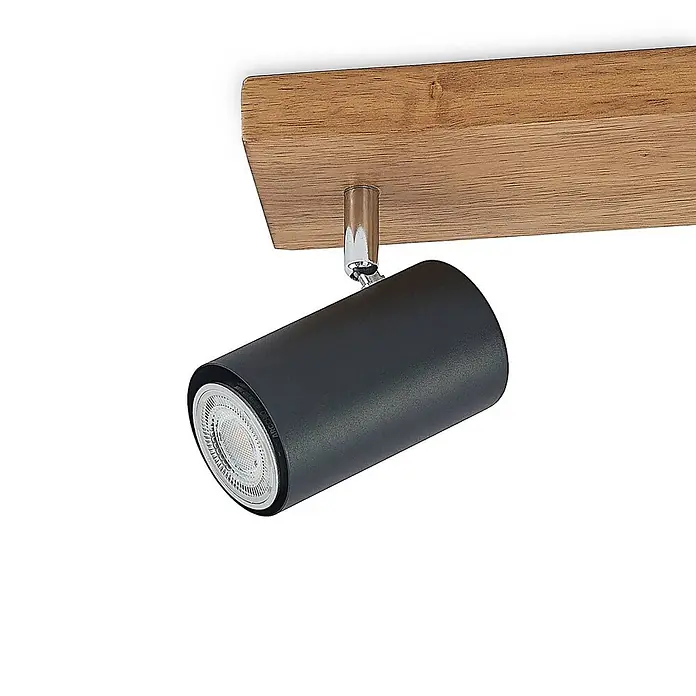 Lindby Deckenstrahler Maniva - Holz hell, schwarz, GU10 - Schwarzer zylindrischer LED-Strahler mit Chrombefestigung, montiert an einer hellbraunen Holzleiste.