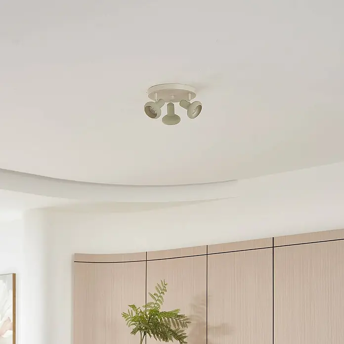 Lindby Deckenstrahler Huby - creme / amber, grün, GU10 - Off-white Deckenleuchte aus Metall mit drei verstellbaren Strahlern auf rundem Sockel, in einem modernen Raum montiert.
