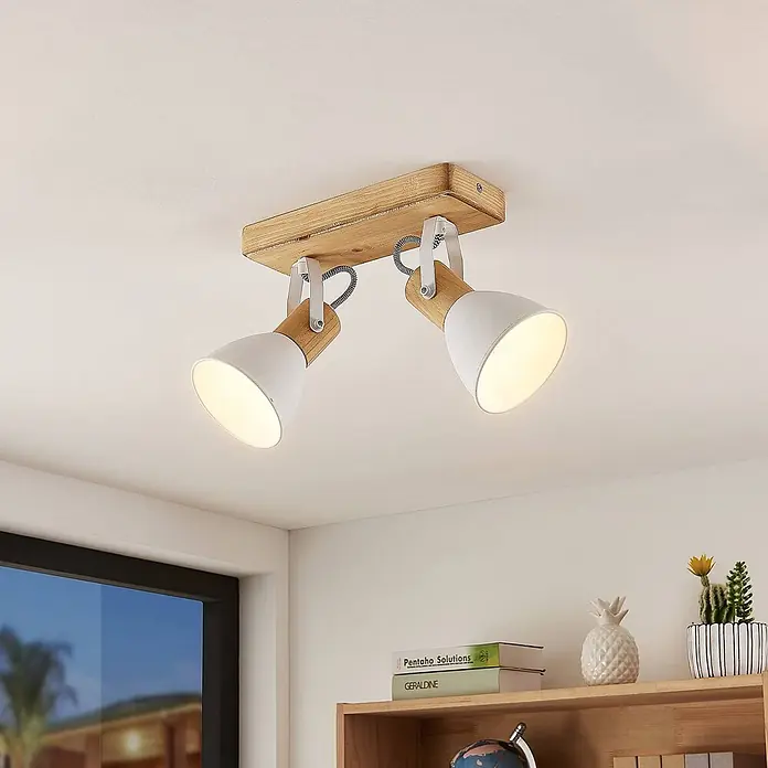 Lindby Deckenstrahler Merela - L x B x H: 28 x 11,5 x 23 cm, Holz hell, E14 - Zweiflammige Deckenleuchte mit heller Holzbasis und weißen Metallschirmen, an der Decke montiert mit eingeschalteten Lichtern.