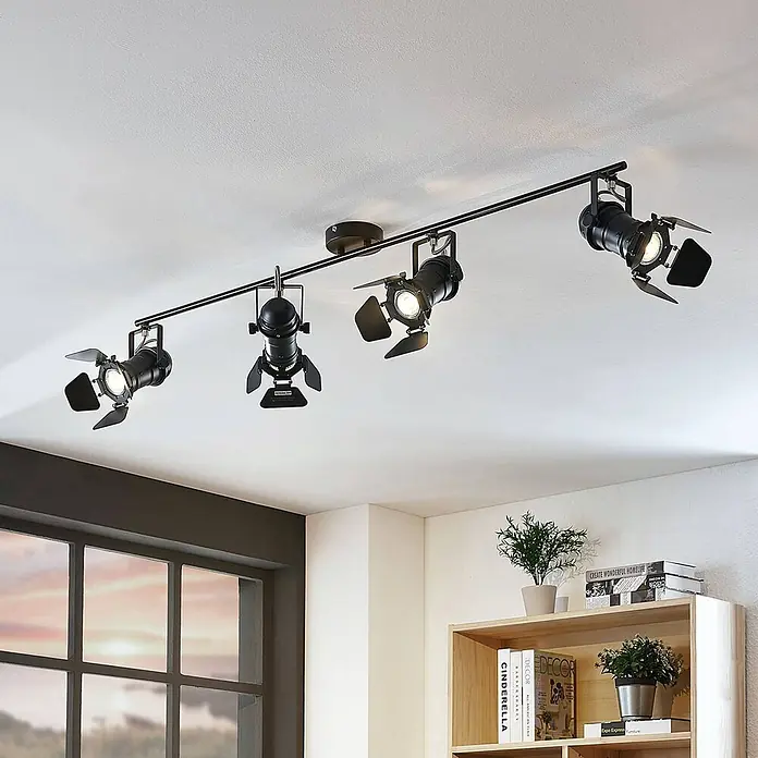 Lindby Deckenstrahler Tilen - schwarz, schwarz, GU10 - Schwarze Metall-Schienenleuchte mit vier verstellbaren Strahlern im Industriestil und Flügeln, an einer weißen Decke montiert.