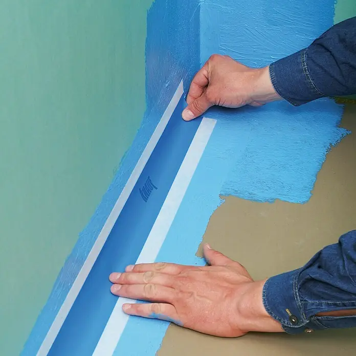 Knauf Flächendichtband - 50 m - Detailaufnahme von Handwerkern, die Abdichtungsband von Knauf an einer Wand anbringen, um eine wasserdichte Barriere zu schaffen.