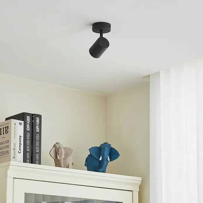 Lindby Deckenstrahler Jorell - schwarz, schwarz, GU10 - Ein schwarzer zylindrischer Deckenstrahler ist an einer Decke montiert und beleuchtet den Raum.