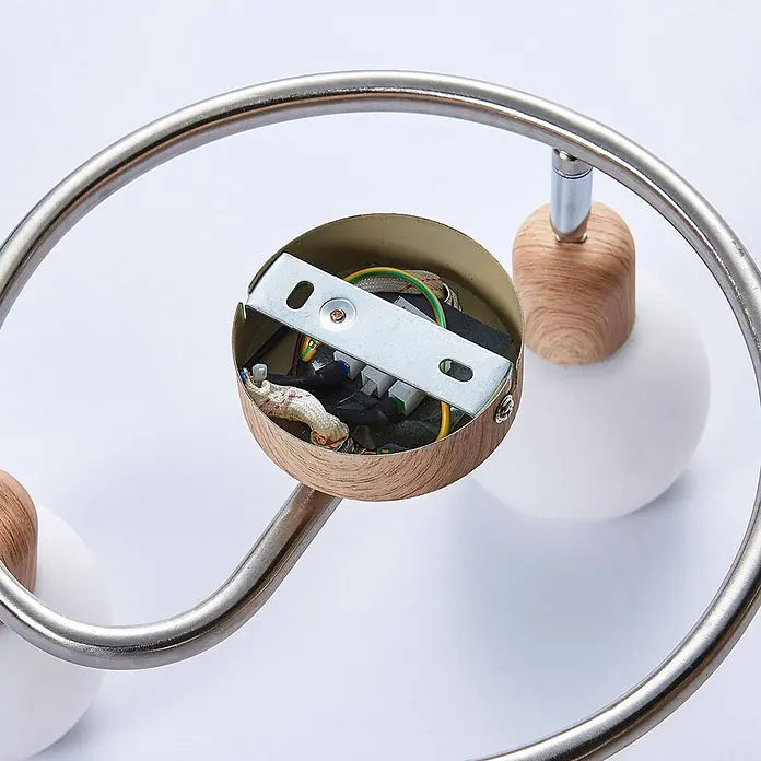 Lindby Deckenstrahler Svenka - Holz hell, E14 - Innenansicht einer Leuchte: Verkabelung und Metallhalterung in einer Holzoptik-Basis, verbunden mit gebürsteten Metallarmen und weißen Kugellampen.