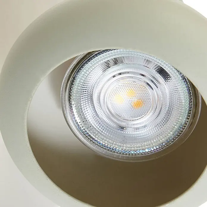 Lindby Deckenstrahler Huby - creme / amber, grün, GU10 - Nahaufnahme eines weißen LED-Strahlers mit texturierter Glaslinse in einer hellbeigen, gebogenen Halterung.