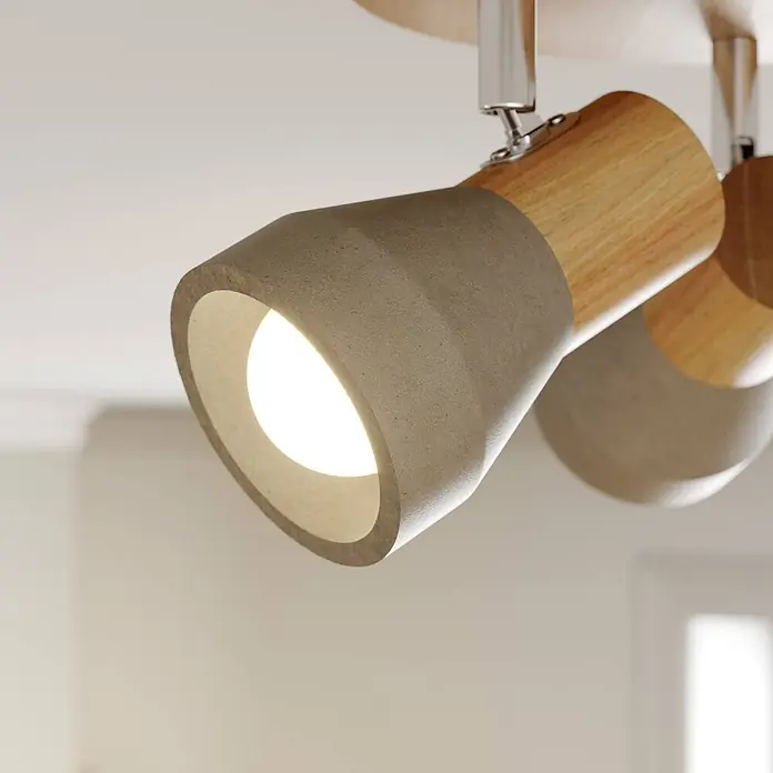 Lindby Deckenstrahler Filiz - Holz hell, alu / grau / zink, E14 - Nahaufnahme eines Deckenstrahlers mit hellem Holzsockel und grauem Beton-Effekt-Kopf, montiert an einer Chromstange.